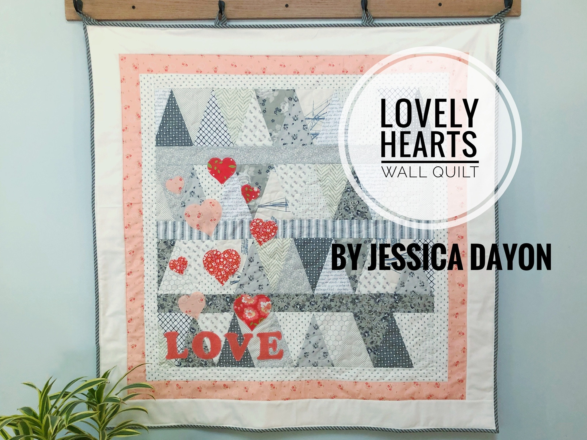 peach grey and white quilted wall hanging made of equilateral triangles and featuring love heart shapes and the word love